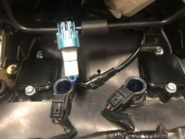 Close-up of a motorcycle ignition switch and wiring harness on a metallic surface.