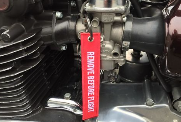 Red 'REMOVE BEFORE FLIGHT' tag on a motorcycle engine