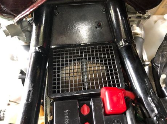 Close-up of a motorcycle's engine compartment with a red fuel tank cap.
