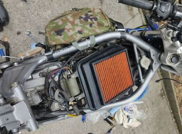 Motorcycle with a camouflage bag on the handlebar, showing mechanical components.