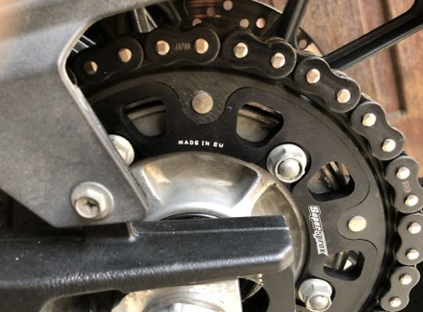 Close-up of a motorcycle chain and sprocket with 'Made in EU' text.