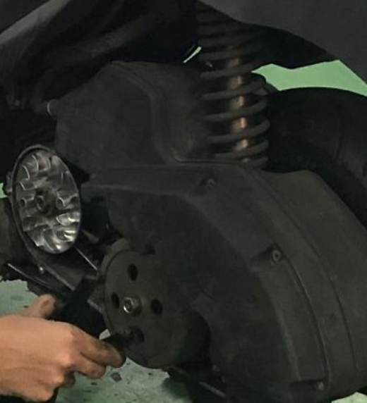 Close-up of a person working on a motorcycle's headlight assembly.