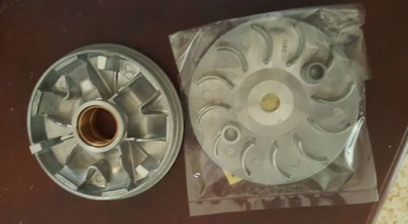Two metal components on a brown surface with one in a clear plastic bag.