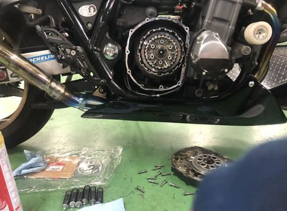 Motorcycle engine with tools and parts on a green workbench