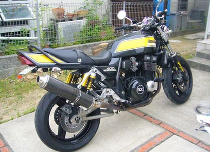Motorcycle parked on a concrete surface with a grassy area and building in the background