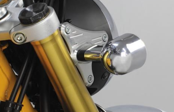 Close-up of a motorcycle's headlight assembly with gold and chrome finish.