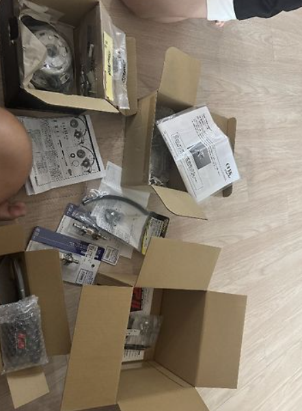 Open cardboard box with electronic components on a wooden floor