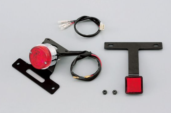 Motorcycle light assembly with red lens and wiring on a gray background