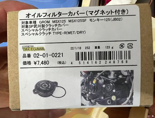 Product packaging with label and barcode, featuring a small engine component image.