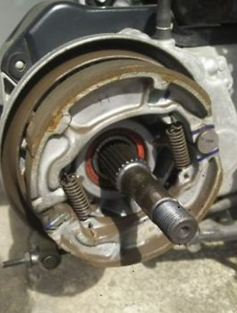Close-up of a mechanical component, possibly a gear or clutch assembly, on a concrete surface.