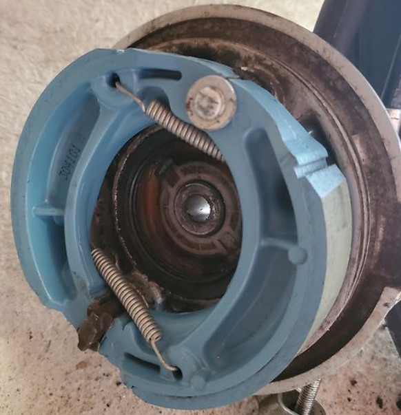 Close-up of a mechanical component with blue housing and springs on a concrete floor.