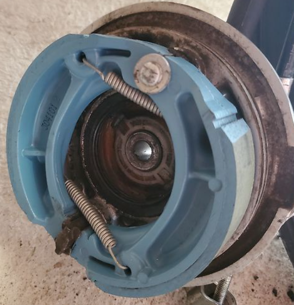 Close-up of a blue mechanical component with springs on a concrete surface
