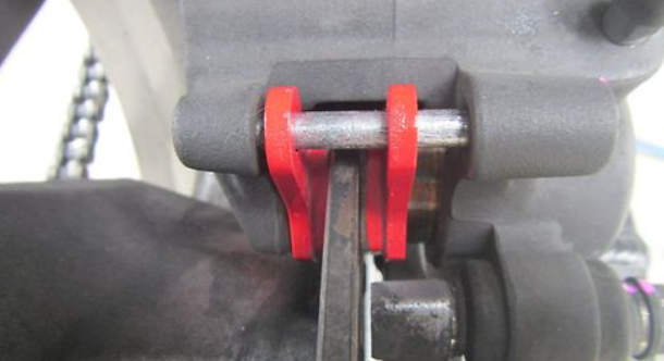 Close-up of a mechanical component with a red strap, likely from a vehicle or machinery.