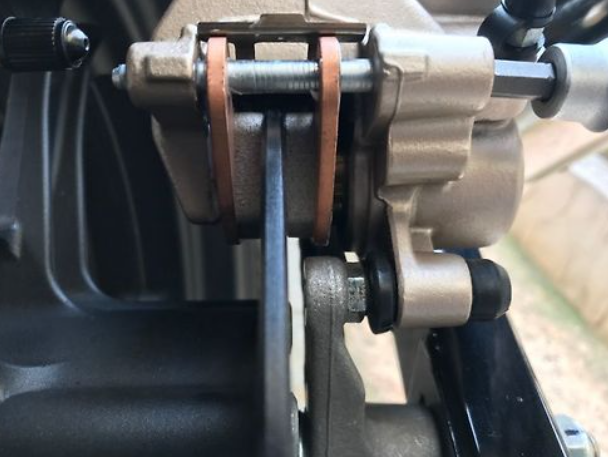 Close-up of a mechanical component, possibly a gear or pulley system, with metal parts and bolts.