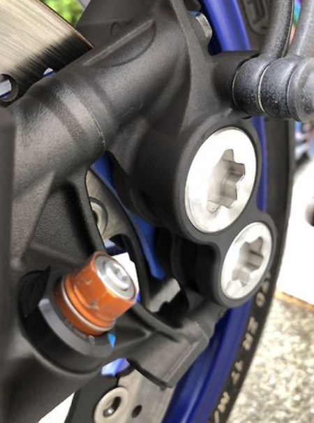 Close-up of a motorcycle's foot peg and brake lever with a blurred background
