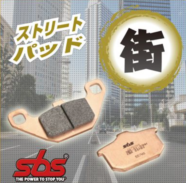 Brake pads with SBS logo and Japanese text on a blurred cityscape background
