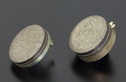 Two round brake pads on a dark background