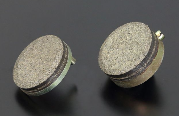 Two round brake pads on a dark background