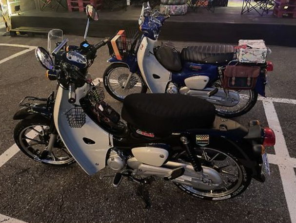 Two motorcycles parked side by side on a street at night.