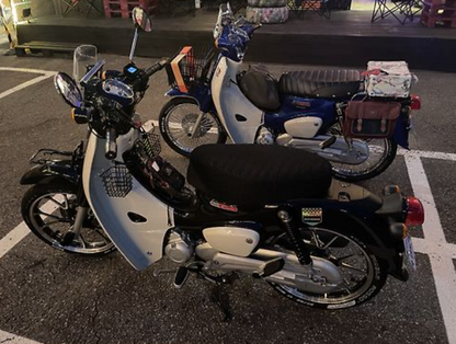Two motorcycles parked side by side on a street at night.