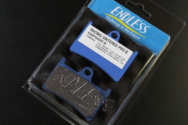 Packaged set of ENDLESS brake pads with blue and black design on a dark background