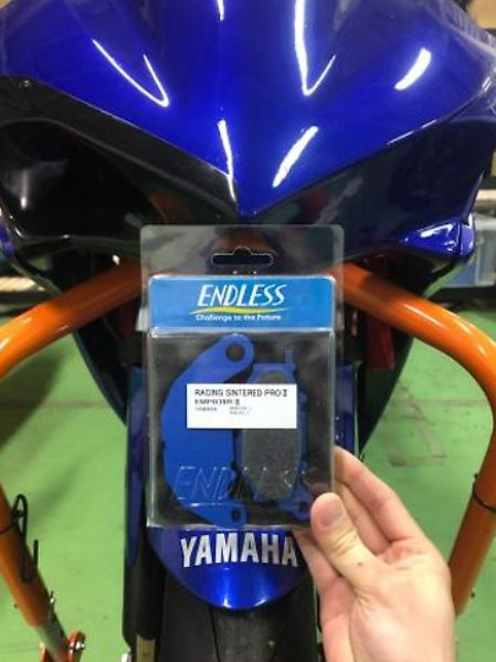 Packaged racing snifter ring held in front of a Yamaha motorcycle