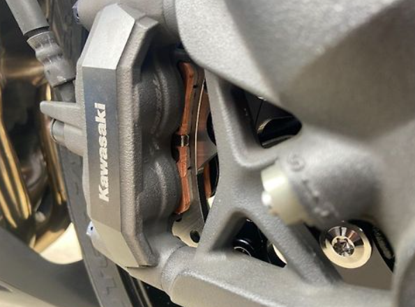 Close-up of a Kawasaki brake caliper with brake pads.
