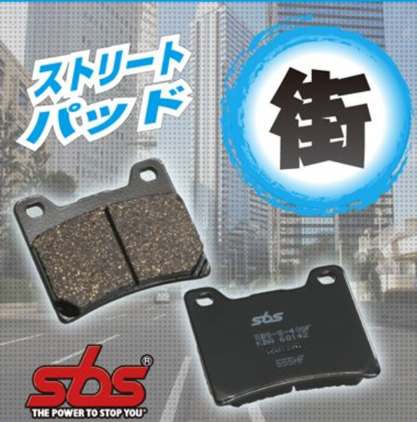 Brake pads with SBS logo and Japanese text on a blurred cityscape background
