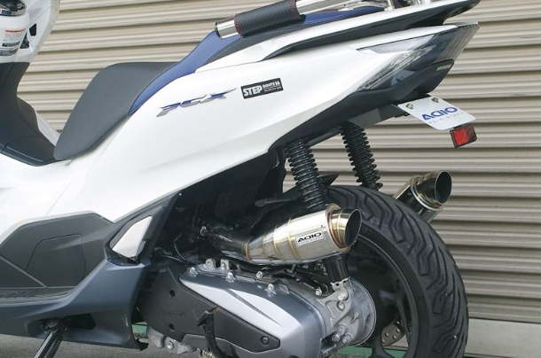 Close-up of a motorcycle with a shiny exhaust pipe against a metallic background