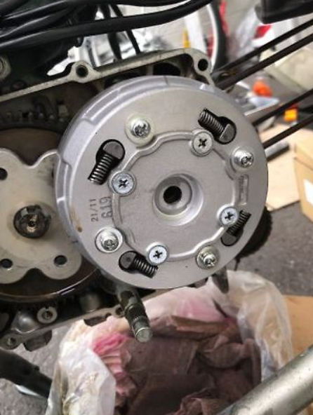 Close-up of a motorcycle engine component with visible bolts and gears.