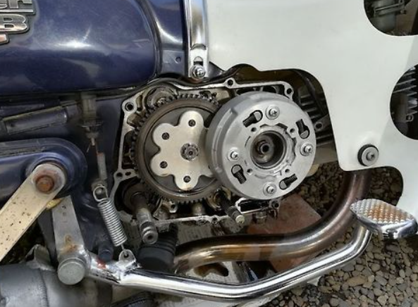 Close-up of motorcycle engine components on a gravel surface