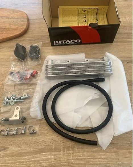 Kitaco motorcycle parts kit on a wooden surface with a cardboard box in the background.