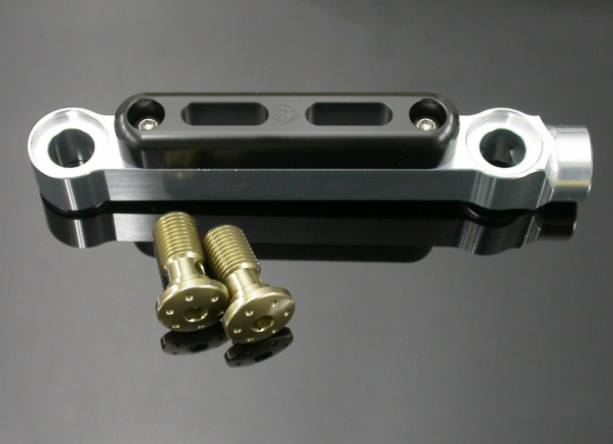 Metal bracket with two screws on a reflective gray surface