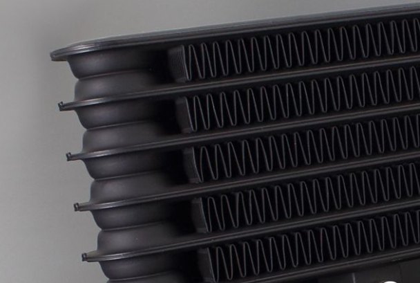 Close-up of a black radiator with ribbed design on a gray background