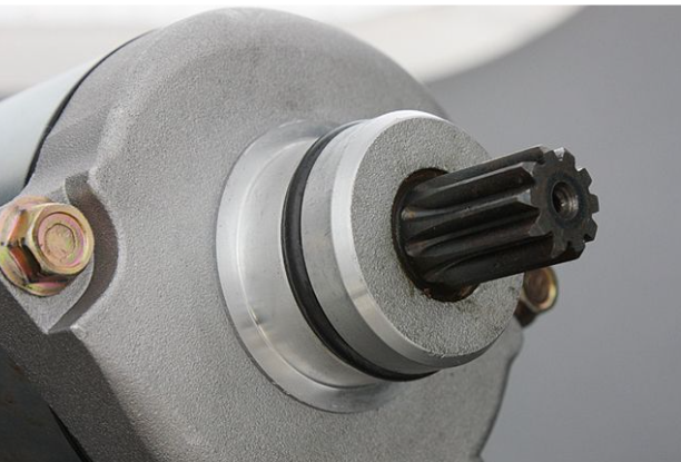 Close-up of a mechanical component with a gear and bolts on a gray background