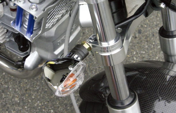 Close-up of a motorcycle's headlight and front suspension on a road.
