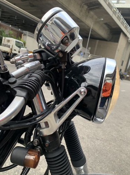 Close-up of a motorcycle handlebar with chrome mirrors and controls.