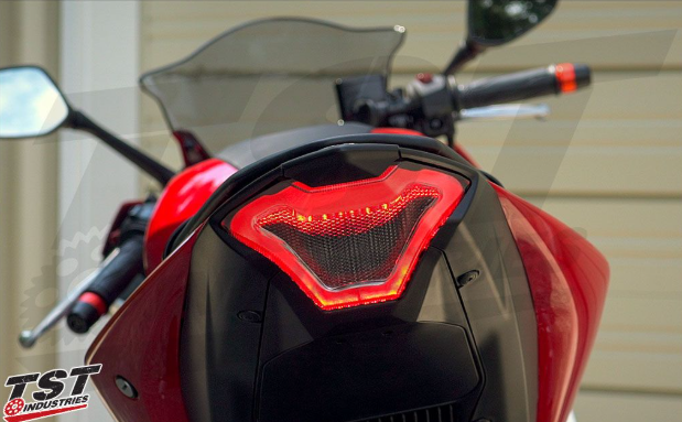 Close-up of a motorcycle's tail light with 'TST Industries' branding.