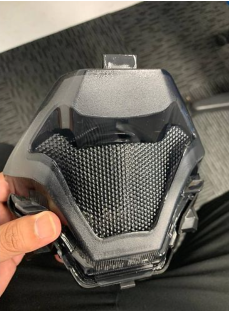 Black and gray textured object held by a hand on a dark background