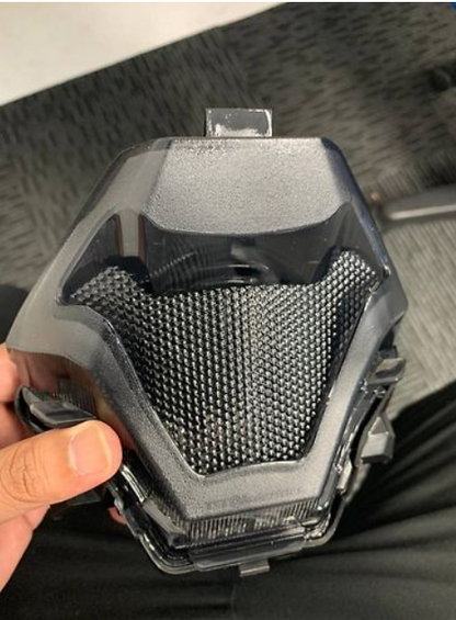 Black and gray textured object held by a hand on a dark background
