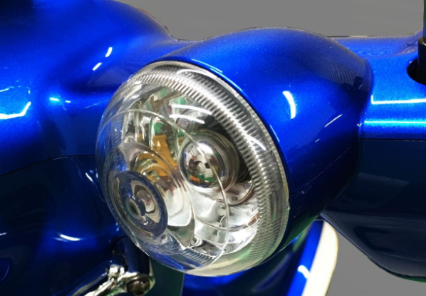 Close-up of a blue motorcycle headlight with a clear lens