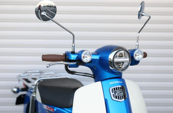 Blue and white scooter with Honda logo against a neutral background