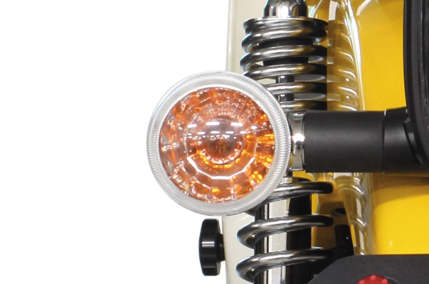 Close-up of a motorcycle headlight with a white rim and orange lens on a white background