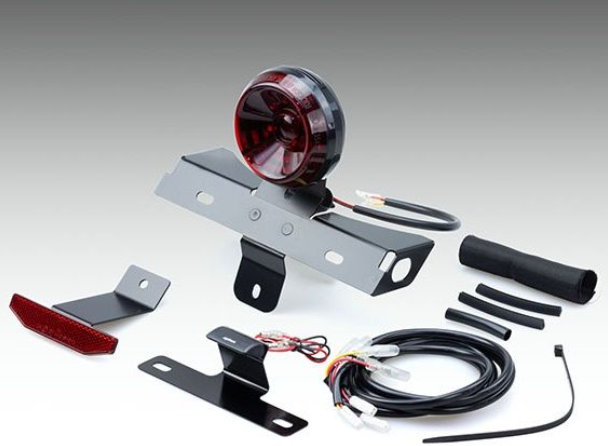 Collection of automotive parts including a red taillight, brackets, and wiring on a gray background