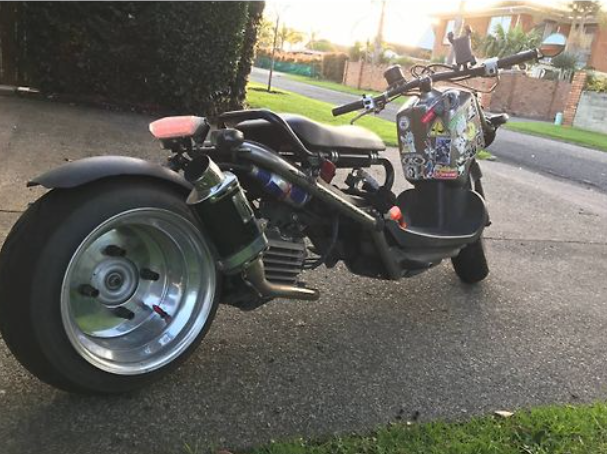 Three-wheeled motorcycle on a driveway with a residential background