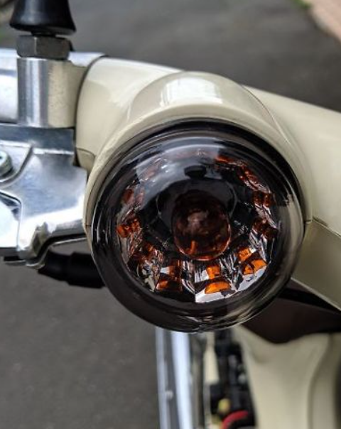 Close-up of a motorcycle headlight with visible wear and tear.