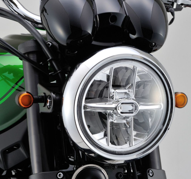 Close-up of a motorcycle headlight with a clear lens and silver frame.