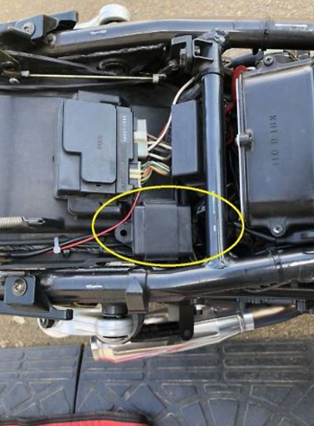 Close-up of a mechanical component with wiring and a yellow circle highlighting a specific part on a vehicle.