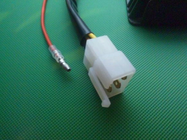 White electrical connector with red and black wires on a green surface