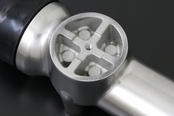 Close-up of a metallic kitchen tool with a textured surface on a dark background